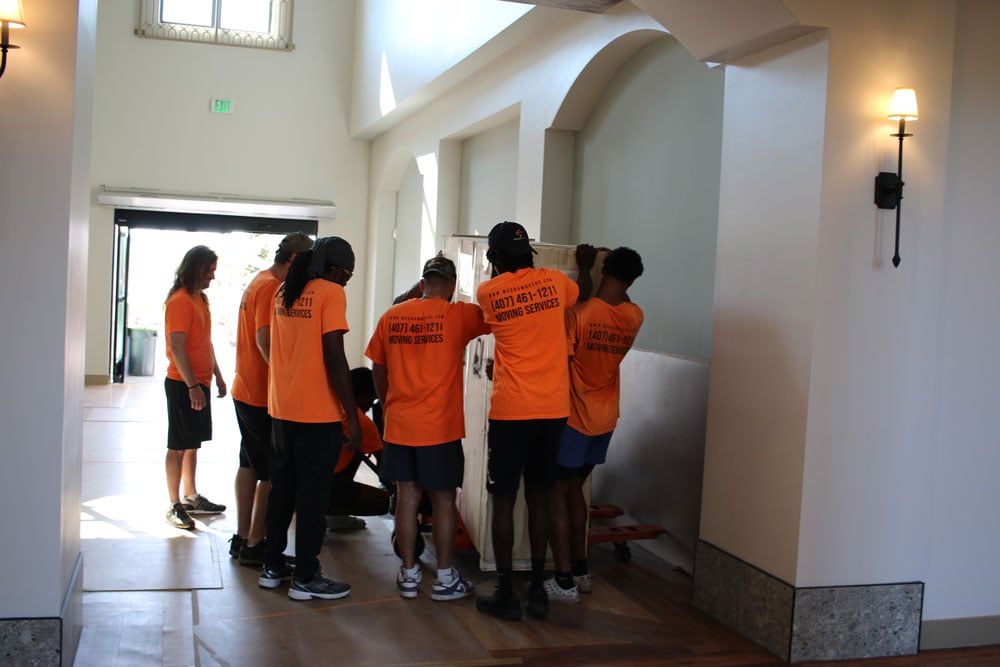 MechaMovers crew carefully maneuvering a wardrobe through a doorway